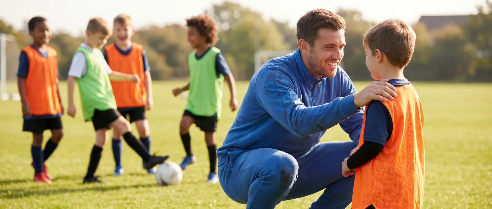 Trainer ermutigt ein Kind auf dem Fußballplatz